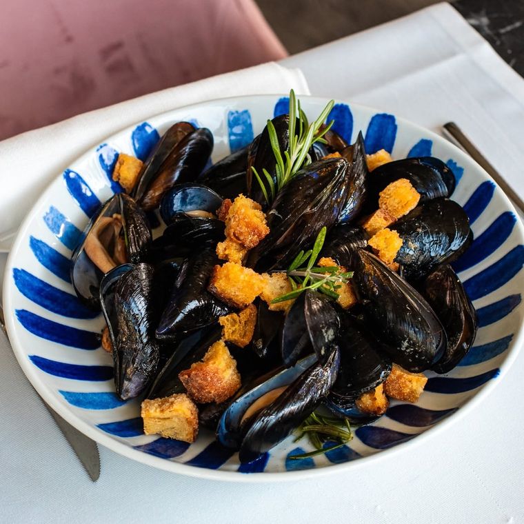 Cozze con crostini e rosmarino in un piatto a righe blu