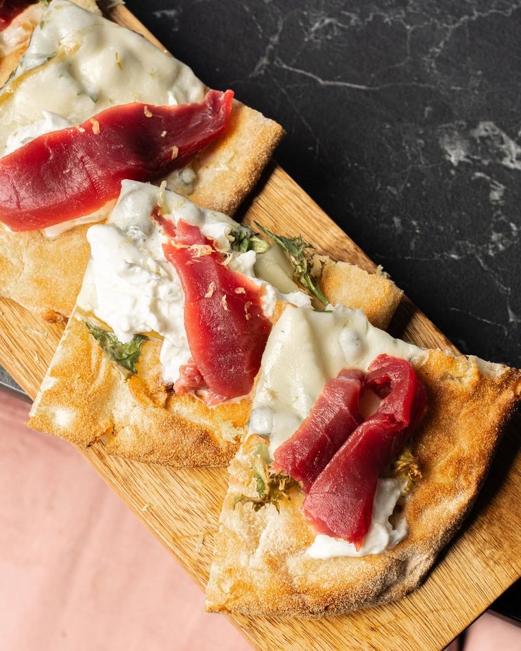 Pizza in pala tagliata a tranci, su tagliere di legno e marmo nero